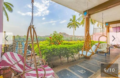 a porch with swings and a view of a garden at Archana Guest House River View in Hampi