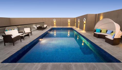 uma piscina num hotel com cadeiras e mesas em Boudl Al Corniche em Dammam