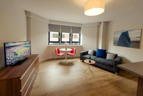 a living room with a couch and a tv at PREMIER SUITES PLUS Glasgow Bath Street in Glasgow