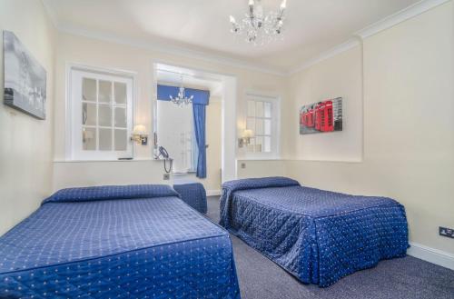 a bedroom with two blue beds and a chandelier at Aaraya Sussex Gardens in London