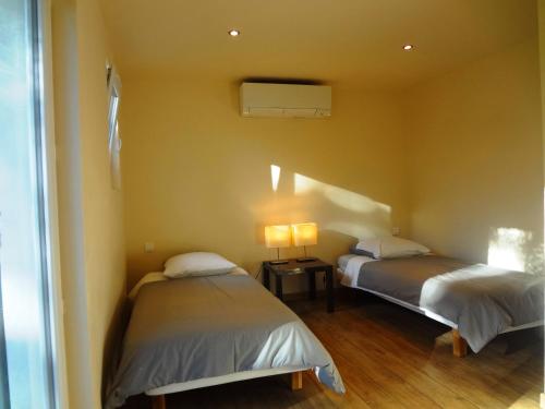 2 lits dans une chambre avec 2 lampes sur une table dans l'établissement Le mazet d'Uzès, à Uzès