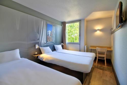 Cette chambre comprend 2 lits, une table et une fenêtre. dans l'établissement B&B HOTEL Beaune Sud 1 Palais des Congrès, à Beaune