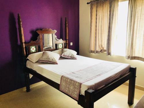 a bedroom with a large bed with purple walls at Goodkarma Inn in Cochin