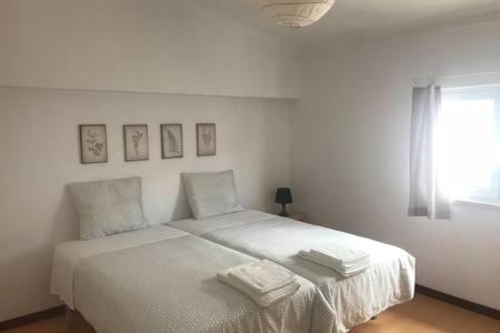 a bedroom with a bed with white sheets and a window at Casa da Avó Tita in Cardeal
