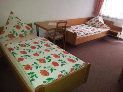 a bedroom with two beds and a table and a table and chair at Moselhotel Waldeck in Burgen