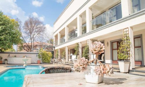 a house with a swimming pool and a wooden table at Gardenia Boutique Hotel in Johannesburg