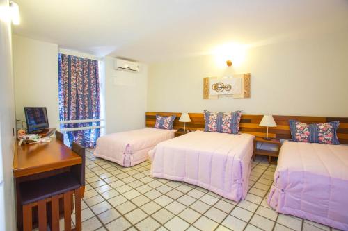 a hotel room with two beds and a desk at Falls Galli Hotel in Foz do Iguaçu
