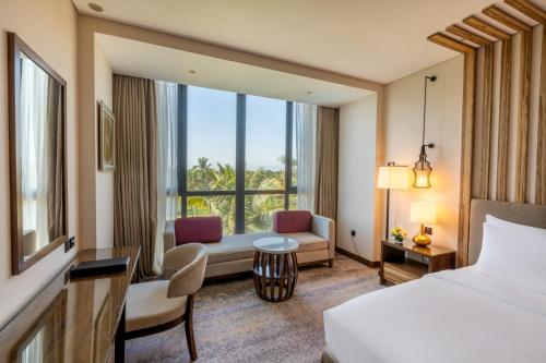 a hotel room with a bed and a living room at Millennium Resort Salalah in Salalah