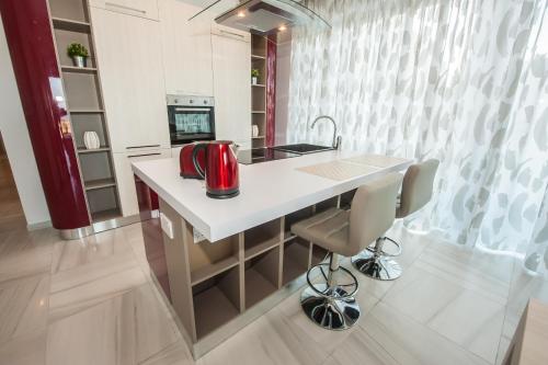 a kitchen with a white island with a red appliance on it at Artist Terrace Apartments in Mellieħa