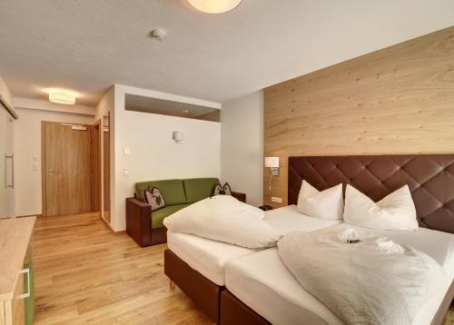 a bedroom with a large bed and a green couch at Hotel Enzian Paznaun in See