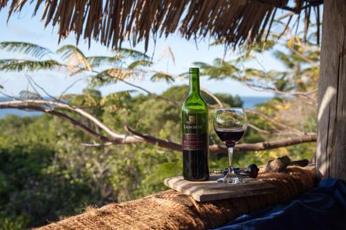 a bottle of wine and a glass on a table at Chole Mjini Treehouses Lodge in Utende