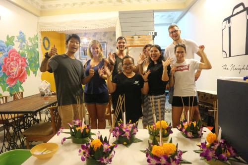 a group of people posing for a picture in a room at The Neighbors Hostel in Phuket Town