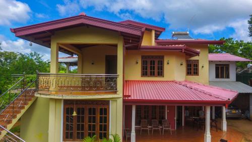 a house with a red roof and a balcony at Sigiriya Peacock Homestay in Sigiriya