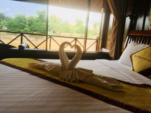 a bed with two swans making a heart on it at Merry Riverside Hotel in Luang Prabang