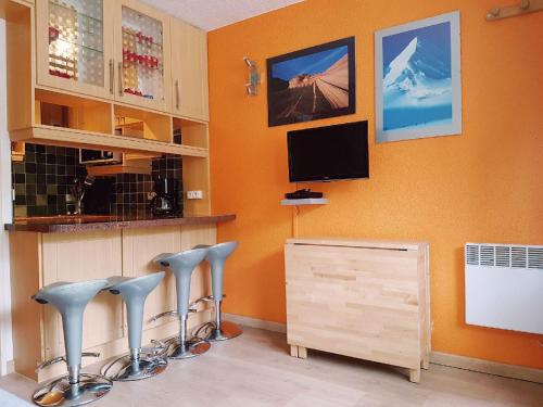 ティーニュにあるStudio au pied des pistes et funiculaireのテレビが備わるオレンジ色の壁の客室です。