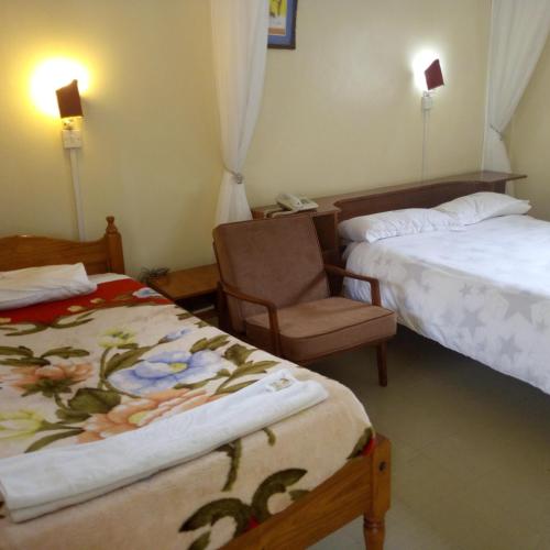a hotel room with two beds and a chair at Adventist LMS Guest House & Conference Centre in Nairobi