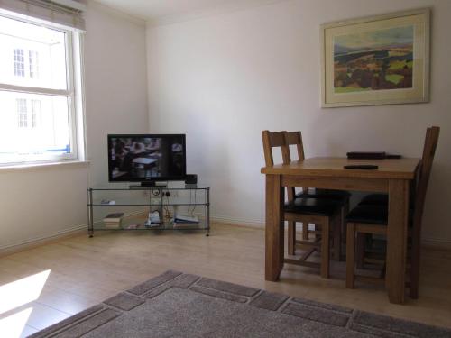 a living room with a table and a television at River Walk Inverness in Inverness
