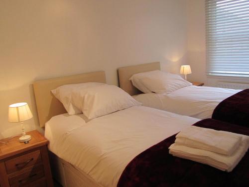 two twin beds in a bedroom with two lamps on a night stand at River Walk Inverness in Inverness