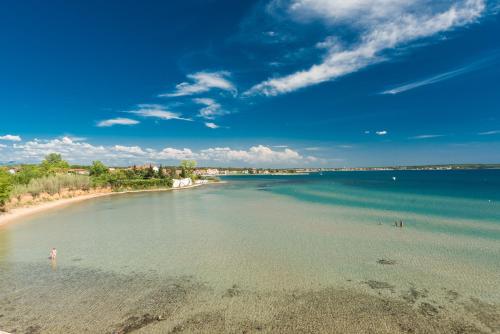 a beach with people swimming in the water at Villa Miri in Privlaka