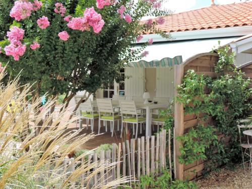 a garden with chairs and a fence with pink flowers at Chambres d'hôtes Villa Surcouf in Andernos-les-Bains