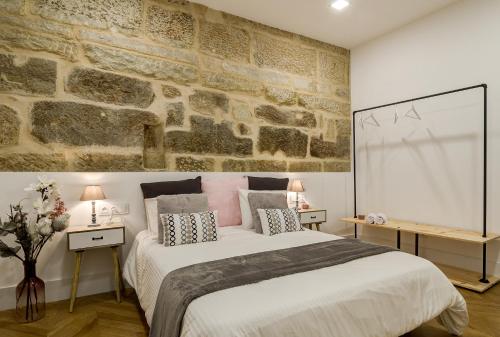 Un dormitorio con una cama grande y una pared de piedra. en Verdura Suites ArchSense Apartments, en Pontevedra
