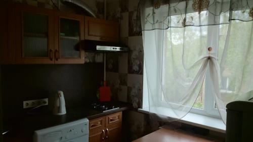 a kitchen with a window with a white curtain at Апартамент в центре города, Stacijas 111 in Daugavpils