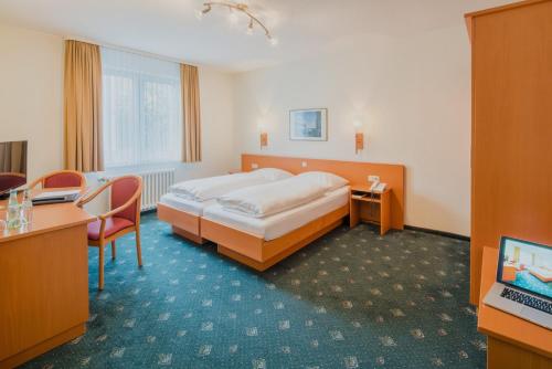 a hotel room with a bed and a desk at Hotel Bitburg in Bitburg