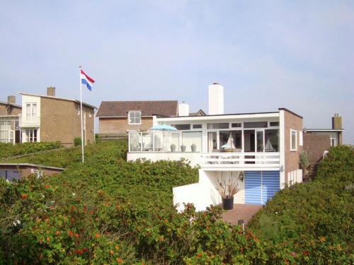 ベルゲン・アーン・ゼーにあるBeautiful house in Bergen aan Zee in the dunesの旗のある丘の上の家