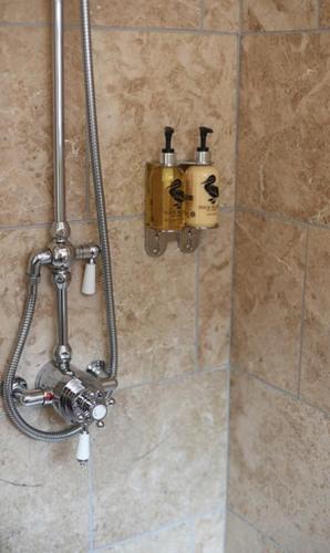 a shower with two soap dispensers on a wall at Woodleighton Cottages in Uttoxeter