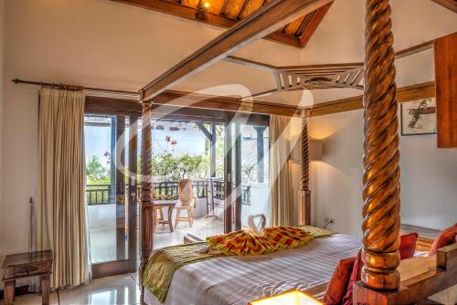 a bedroom with a canopy bed with a balcony at Vila Ultima Bali in Seminyak