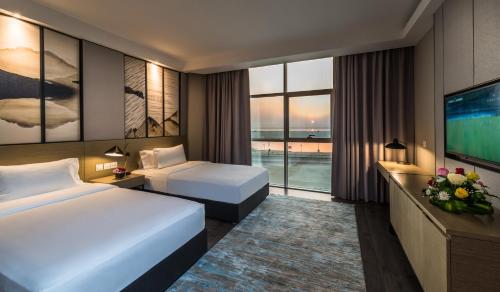 a hotel room with two beds and a flat screen tv at Boudl Al Corniche in Dammam