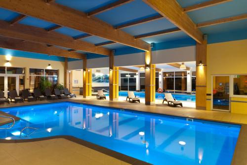 ein Schwimmbad in einem Hotel mit Stühlen und Tischen in der Unterkunft Ośrodek Wypoczynkowo-Rehabilitacyjny "Bryza" in Dźwirzyno