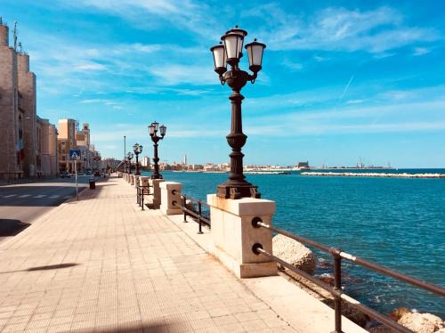 eine Reihe von Straßenbeleuchtung auf einem Bürgersteig neben dem Wasser in der Unterkunft Dimora Vallisa in Bari