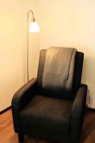 a chair sitting next to a lamp in a room at Hotelli Salpa in Luumäki
