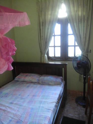 a bedroom with a bed with a window and a fan at Colombo 20 minutes by train in Wattala