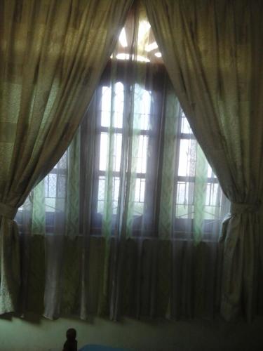 a person sitting in front of a window with curtains at Colombo 20 minutes by train in Wattala