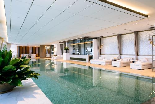 a pool in a hotel with white couches and a lobby at Rosewood Phnom Penh in Phnom Penh
