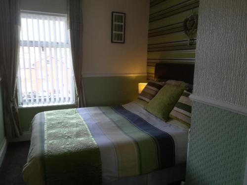 a bedroom with a bed with a colorful blanket at Delamere Hotel in Blackpool