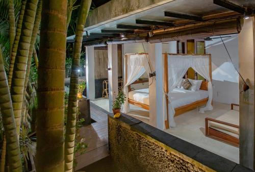 a bedroom with two beds on a balcony with palm trees at Anginsepoi in Canggu