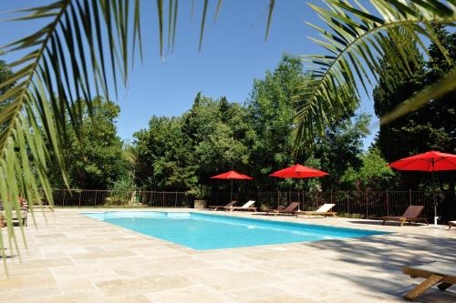 a swimming pool with red umbrellas and lounge chairs at Chambres d'Hotes Domaine des Machottes in Grans