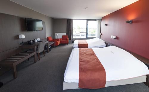 Habitación de hotel con 2 camas, mesa y sillas en Hotel Rastelli Tervuren en Tervuren