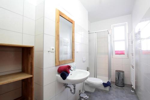 a white bathroom with a sink and a toilet at Yachthafendomizil 2 in Greifswald