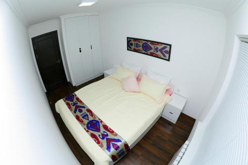 a small bedroom with a bed with white sheets and pink pillows at Apartment on Registon Kochasi in Samarkand