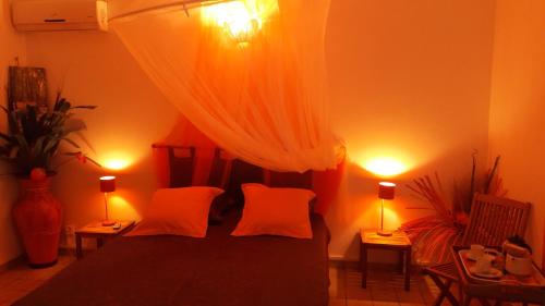 um quarto com uma cama com duas almofadas laranja em Bungalow PAPAYE em Pointe-Noire