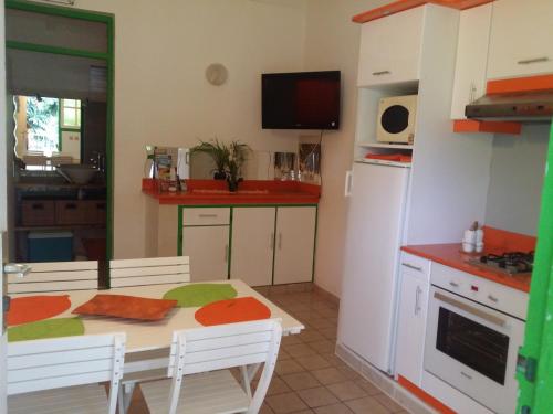 a kitchen with a dining table and a kitchen with a refrigerator at Bungalow PAPAYE in Pointe-Noire