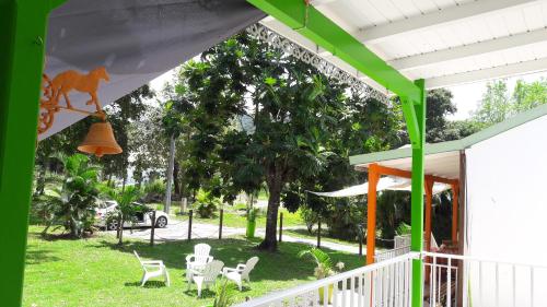 a yard with chairs and a porch with a tree at Bungalow PAPAYE in Pointe-Noire