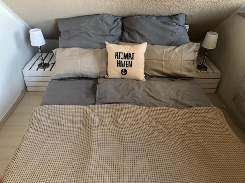 een bed met grijze lakens en kussens in een slaapkamer bij „Little Hamptons“ in Grömitz