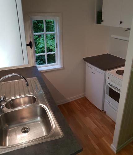 a kitchen with a stainless steel sink and a window at Stuga på Hallandsåsen in Hjärnarp