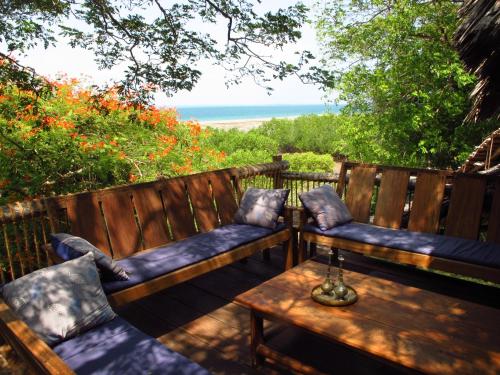 two benches with pillows and a table on a patio at Chole Mjini Treehouses Lodge in Utende