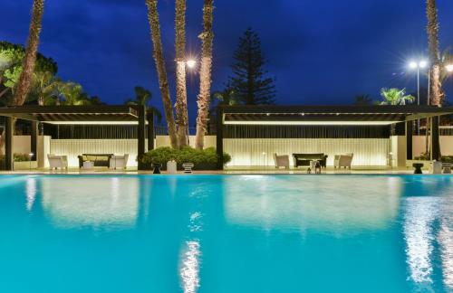 a swimming pool at night with palm trees at Hotel Cerere in Paestum